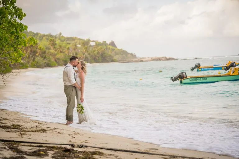 Jennifer & Daniel – couple standing in shallow water on a beach with a boat behind