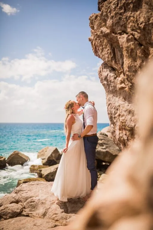 Couple kissing on granite rocks by the sea in the Seychelles